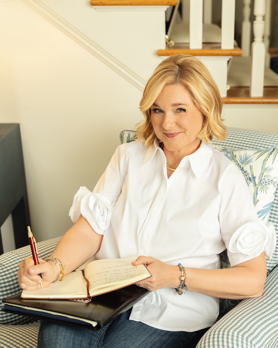 Lisa writing in a journal, seated in a blue gingham armchair